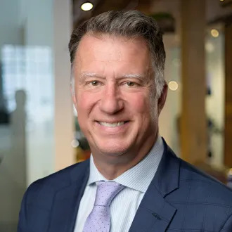A person in a suit smilingDescription automatically generated